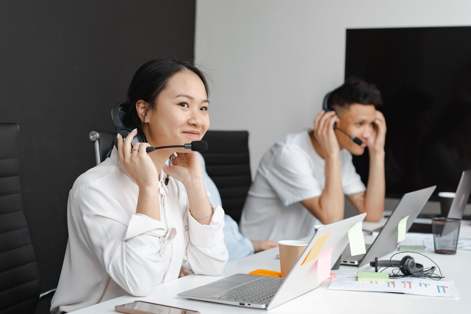 Two support agents wearing headsets at their desks, comparing offshore outsourcing in India with US hiring costs